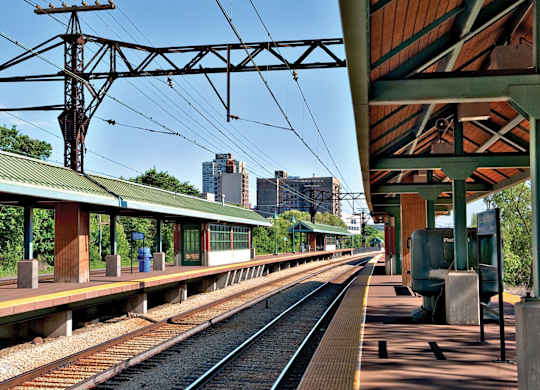 A train station with a green roof and a train on the tracks.