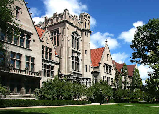 A large building with a red roof and a green lawn in front.