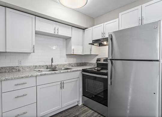 a kitchen with white cabinets and a stainless steel refrigerator