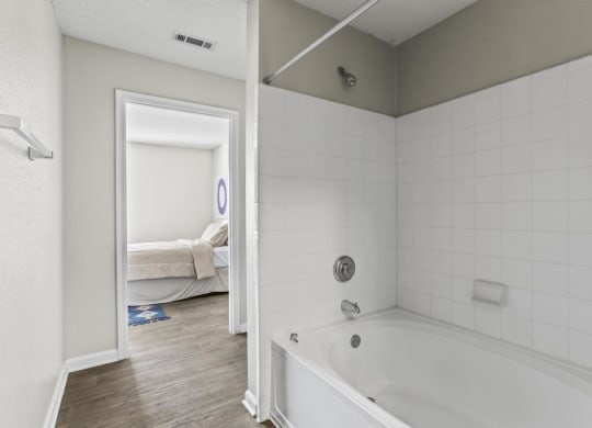 a white bathroom with a tub and a bedroom