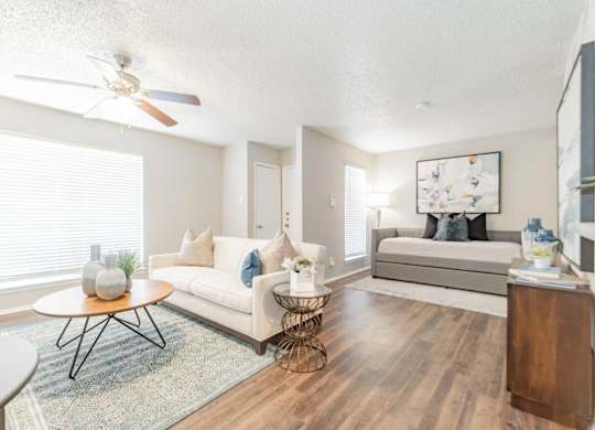 a spacious living room with a ceiling fan and hardwood flooring
