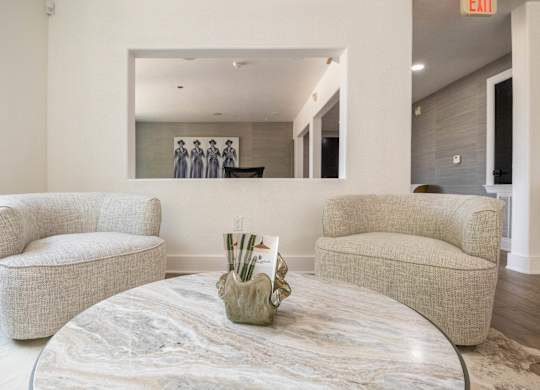 A living room with a round marble table and two chairs.