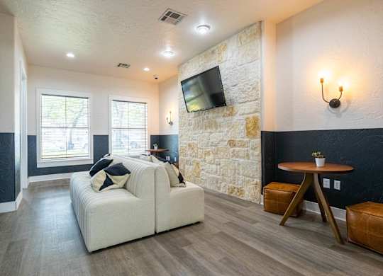 A living room with a white couch and a stone wall.