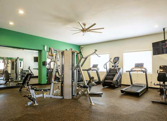 A gym with a variety of equipment including treadmills, stationary bikes, and weight machines.
