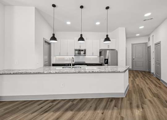 A modern kitchen with a marble countertop and pendant lights.