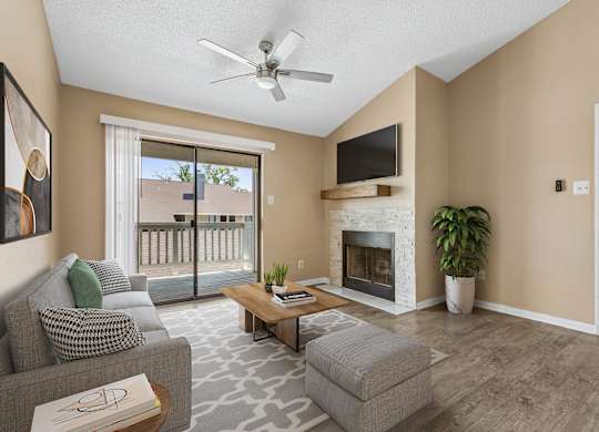 A living room with a grey couch, a coffee table, a fireplace, and a flat screen TV mounted above the fireplace.