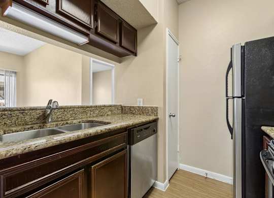 A kitchen with brown cabinets and a black refrigerator.