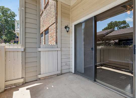 A patio area with a sliding glass door and a wooden fence.