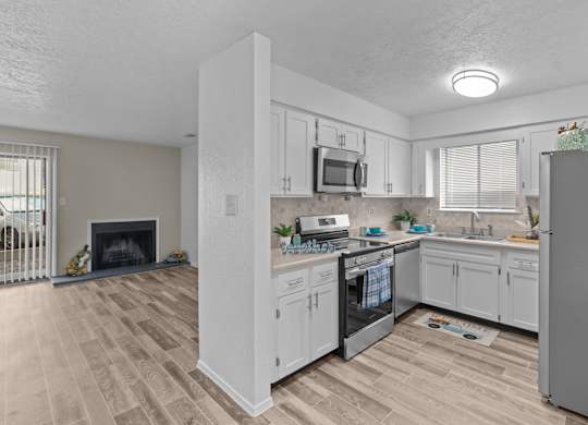 A kitchen with white cabinets and a wooden floor.
