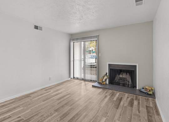 A living room with a fireplace and a window with curtains.