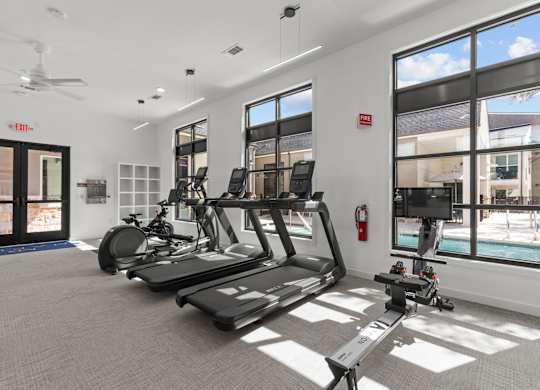 A gym with treadmills, exercise bikes, and a television.