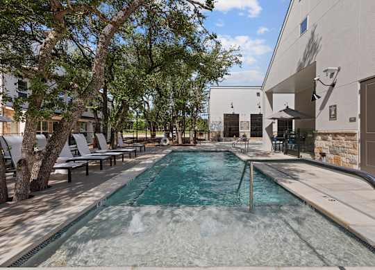 A pool with a slide and trees around it.