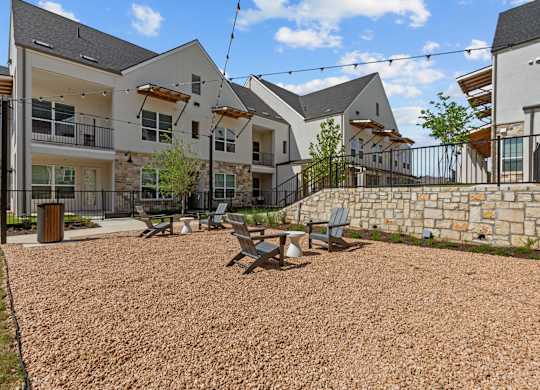 A gravel courtyard with a picnic table and chairs in front of apartment buildings.