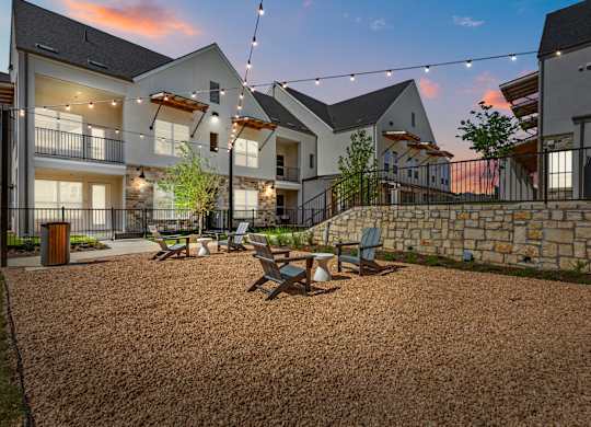A sunset view of a courtyard with a gravel ground and a stone wall.