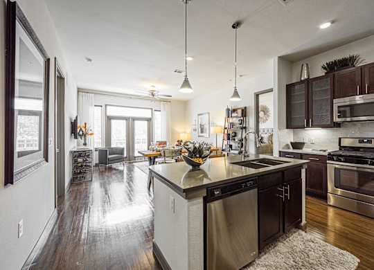 A modern kitchen with dark wood floors and stainless steel appliances.
