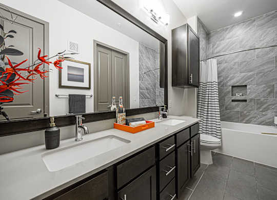 A bathroom with a sink, mirror, and bathtub.