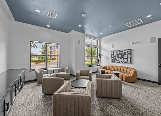 A spacious room with grey carpet and a variety of seating options.
