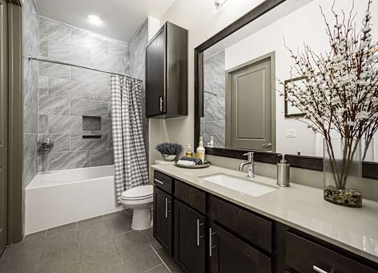 A bathroom with a black cabinet and a white sink.