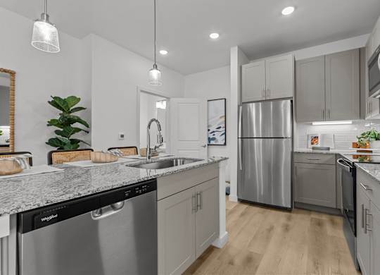 A modern kitchen with stainless steel appliances and wooden floors.