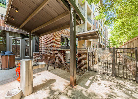 A patio area with a bench, a table, and a trash can.