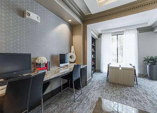 A room with a desk, chairs, and a computer monitor.