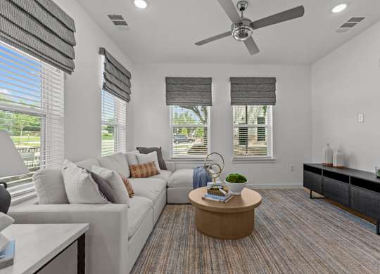 A living room with a white couch, a wooden coffee table, and a ceiling fan.