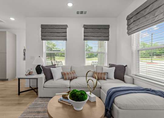 A living room with a white couch, a coffee table, and a window with blinds.