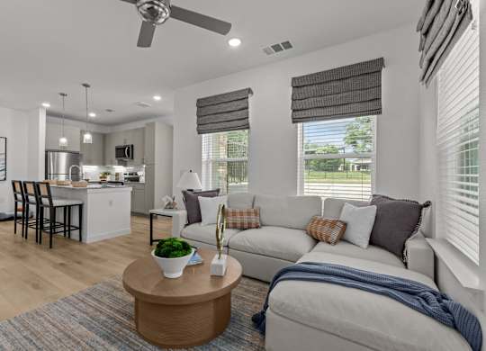 A modern living room with a kitchen in the background.