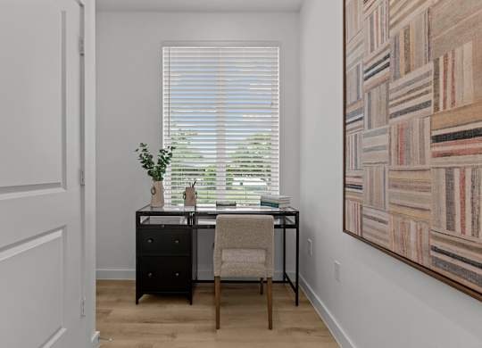 A room with a desk, chair, and a painting on the wall.