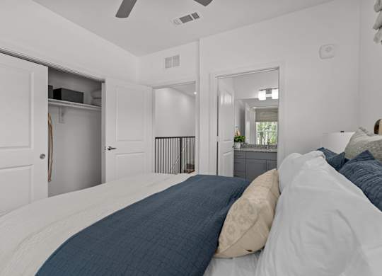 A bedroom with a bed, pillows, and a ceiling fan.