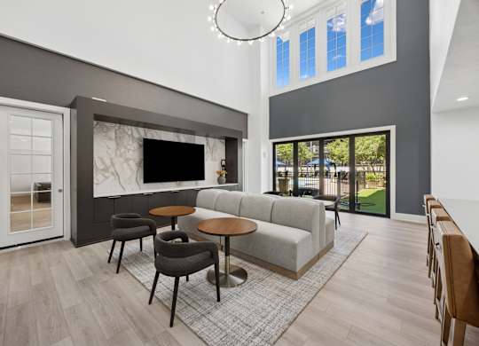 A modern living room with a grey sofa, a round table, and a television.