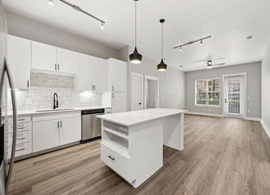 A modern kitchen with a white island and wooden floors.