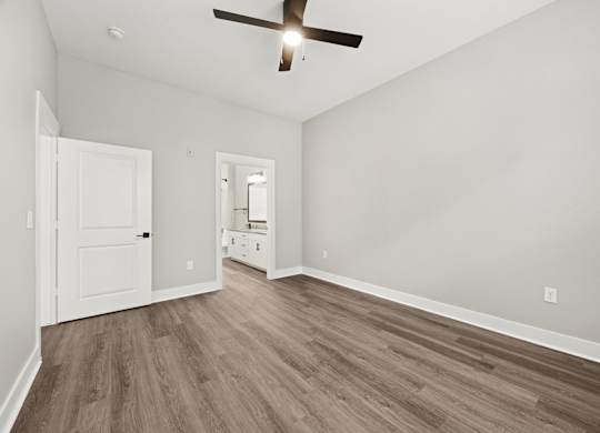 A room with a ceiling fan and wood flooring.