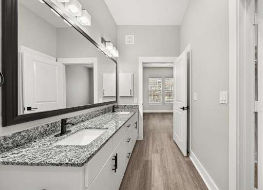 A bathroom with a marble countertop and white cabinets.