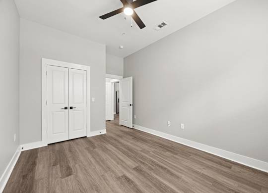 A room with a ceiling fan and wooden flooring.