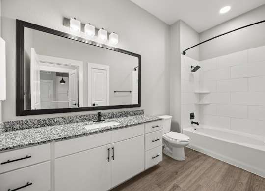 A bathroom with a large mirror, sink, toilet, and bathtub.