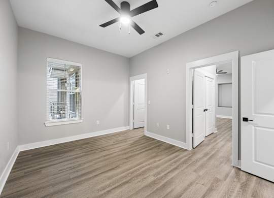 A room with a ceiling fan and a window with blinds.