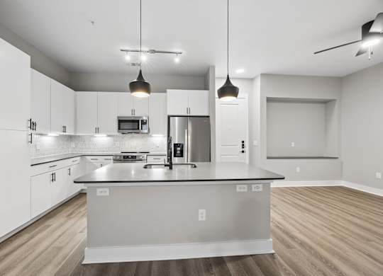 A modern kitchen with a large island and pendant lights.