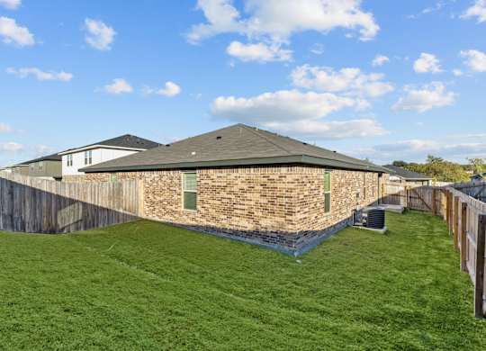 the back of a brick house with a backyard and a fence