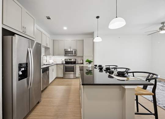 A modern kitchen with stainless steel appliances and wooden flooring.