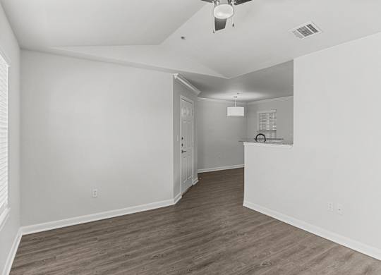 an empty living room and kitchen with white walls and wood flooring