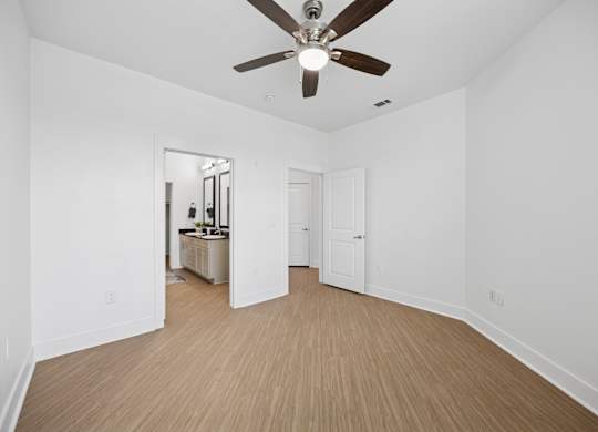 A room with a ceiling fan and wooden flooring.