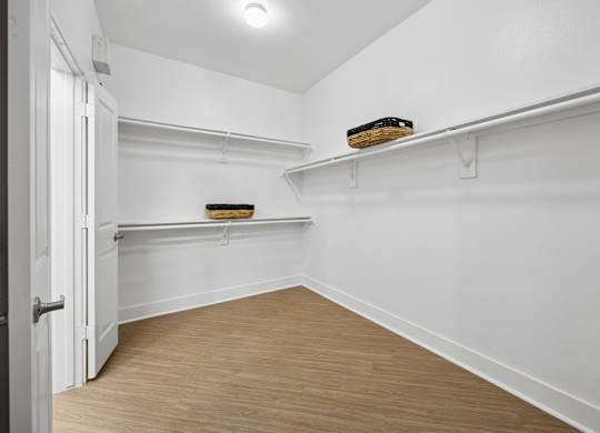A white room with a wooden floor and a door on the left.