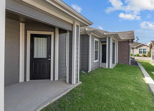 a home with a black door and a sidewalk in front of it