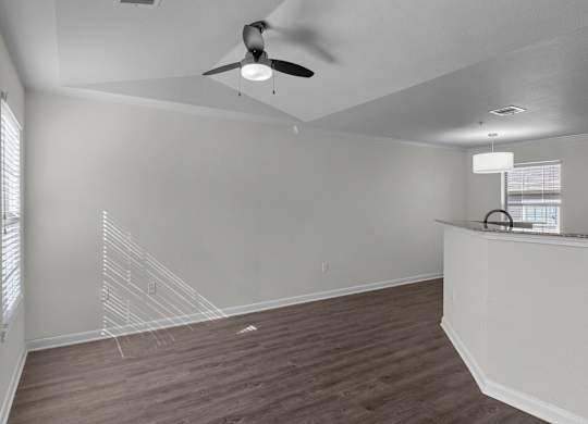 an empty living room with white walls and a ceiling fan