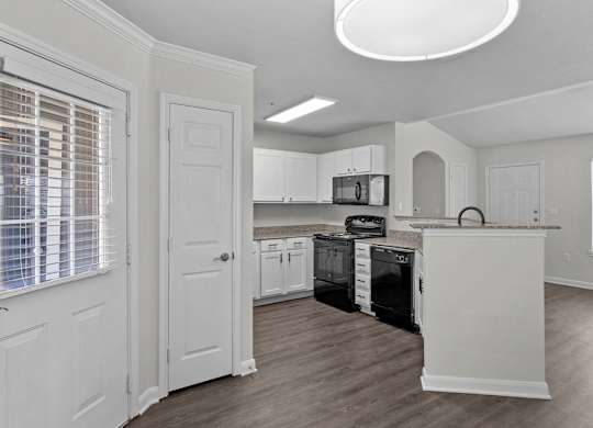 an empty kitchen with white cabinets and a black stove and