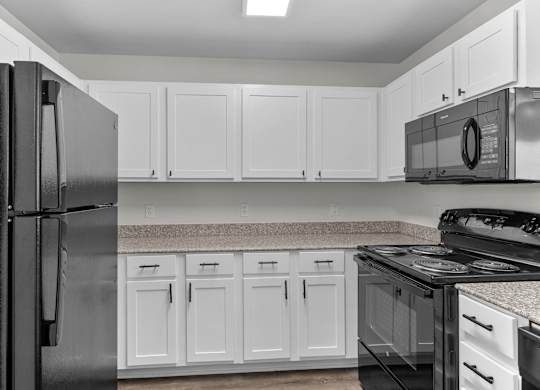 a kitchen with white cabinets and black appliances and a refrigerator