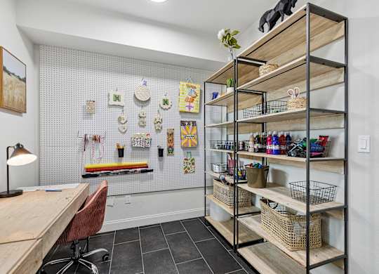 A room with a desk, chair, and shelves filled with various items.