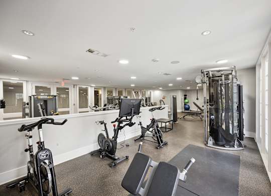 A spacious gym with a variety of equipment including treadmills, stationary bikes, and weight machines.
