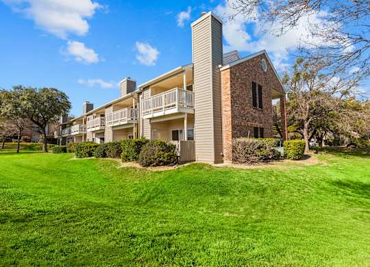 A large grassy area in front of a building with a balcony.